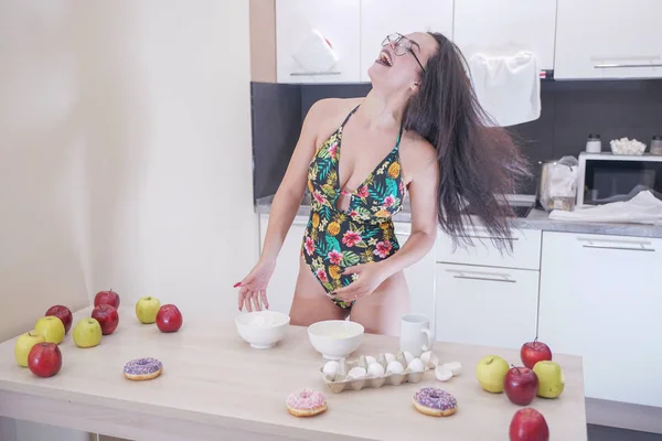 Femme heureuse en maillot de bain à la mode avec des feuilles vertes posant dans la cuisine blanche — Photo