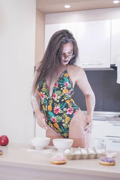 Femme heureuse en maillot de bain à la mode avec des feuilles vertes posant dans la cuisine blanche — Photo