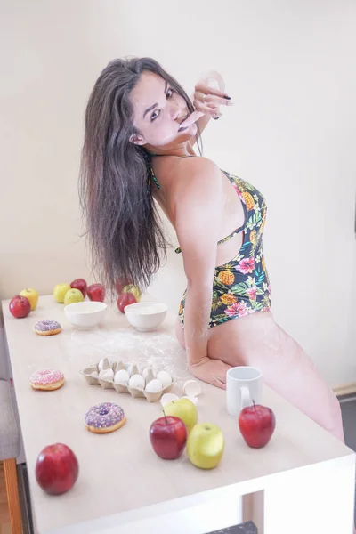 Mujer feliz en traje de baño de moda con hojas verdes posando en cocina blanca —  Fotos de Stock