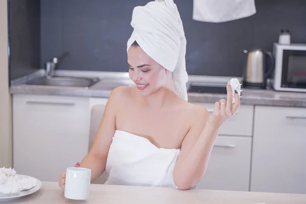 Młoda dziewczyna siedzi w kuchni po prysznicem owinięte w białym ręczniku i odpoczynku — Zdjęcie stockowe