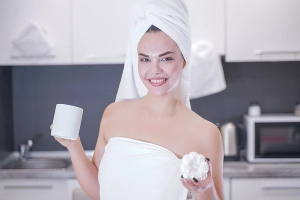 Young girl sitting in the kitchen after a shower wrapped in a white towel and resting — Stockfoto