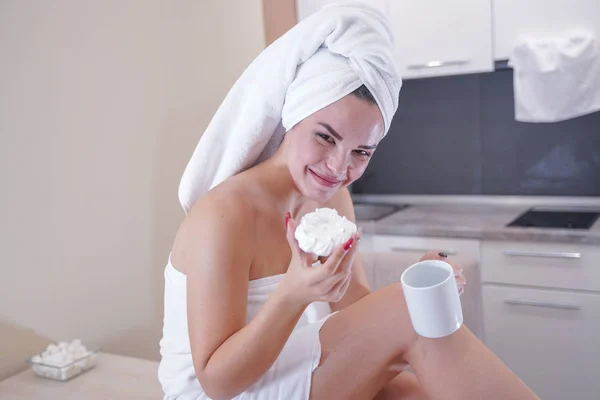 Young girl sitting in the kitchen after a shower wrapped in a white towel and resting — Stockfoto