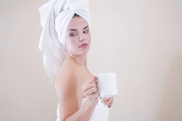 Young girl sitting in the kitchen after a shower wrapped in a white towel and resting — Stockfoto