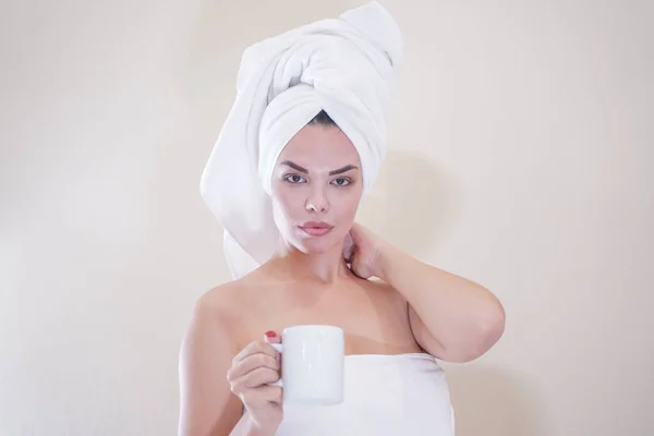 Young girl sitting in the kitchen after a shower wrapped in a white towel and resting — Stockfoto