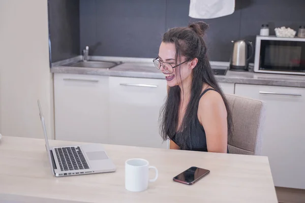 Menina bonito com óculos sentados à mesa com um laptop em casa sozinho — Fotografia de Stock