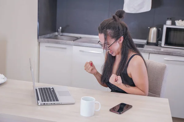 Menina bonito com óculos sentados à mesa com um laptop em casa sozinho — Fotografia de Stock