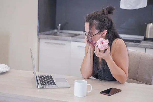 Menina bonito com óculos sentados à mesa com um laptop em casa sozinho — Fotografia de Stock