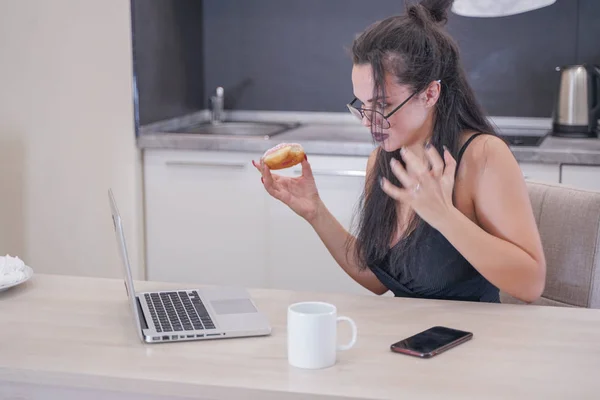 Menina bonito com óculos sentados à mesa com um laptop em casa sozinho — Fotografia de Stock