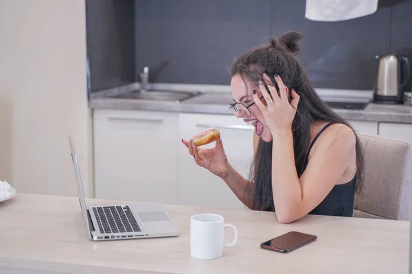 Menina bonito com óculos sentados à mesa com um laptop em casa sozinho — Fotografia de Stock