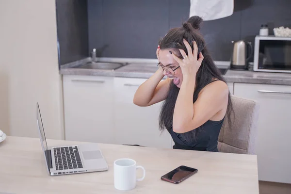 Menina bonito com óculos sentados à mesa com um laptop em casa sozinho — Fotografia de Stock