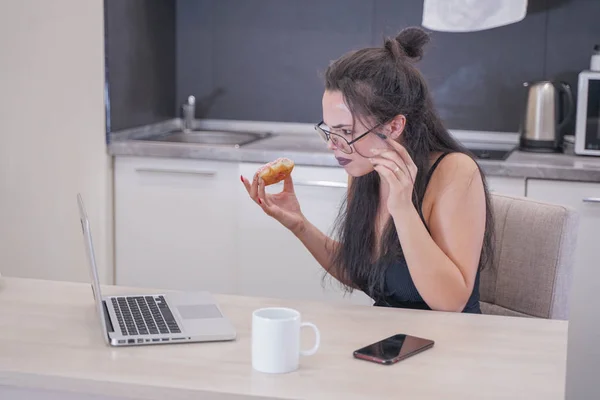 Menina bonito com óculos sentados à mesa com um laptop em casa sozinho — Fotografia de Stock