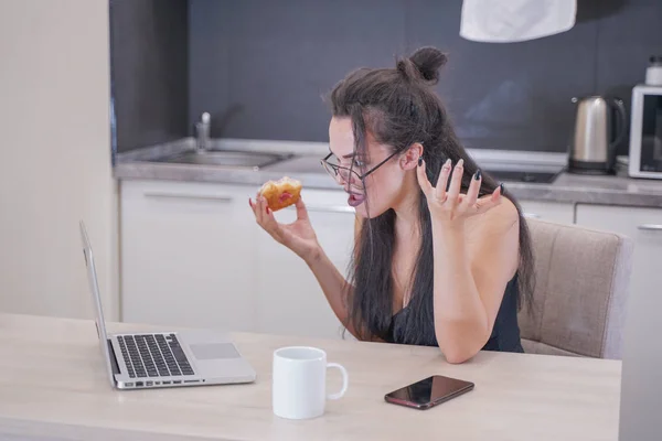 Menina bonito com óculos sentados à mesa com um laptop em casa sozinho — Fotografia de Stock