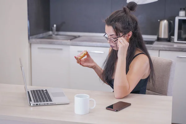 Menina bonito com óculos sentados à mesa com um laptop em casa sozinho — Fotografia de Stock