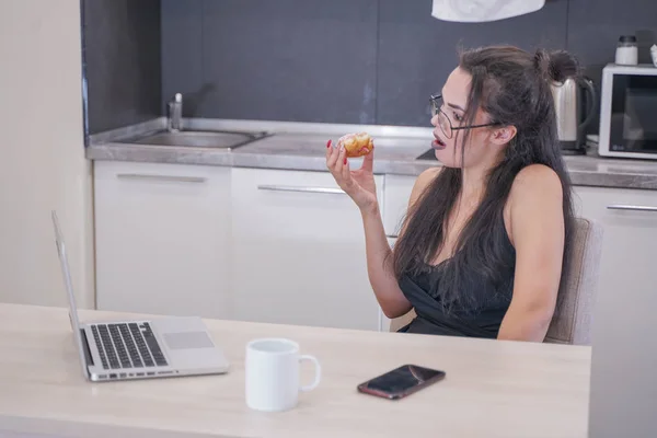 Menina bonito com óculos sentados à mesa com um laptop em casa sozinho — Fotografia de Stock