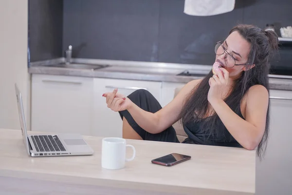 Menina bonito com óculos sentados à mesa com um laptop em casa sozinho — Fotografia de Stock