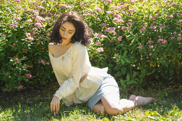 Closeup face of mature woman enjoying the sun at the city park. Beautiful lady relaxing near the green grass and trees.
