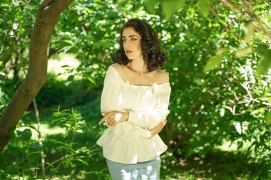 beyaz elbise güzel genç esmer kız şehir parkında ağacın gölgesinde sıcak güneşten gizlemek