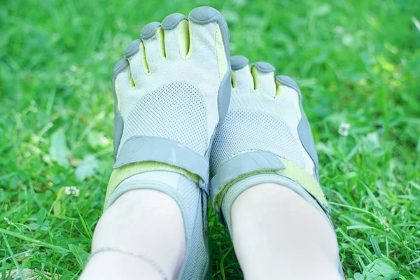 Zapatillas inusuales con cinco dedos. zapatos extraños en verano en verde Parque en la hierba . — Foto de Stock