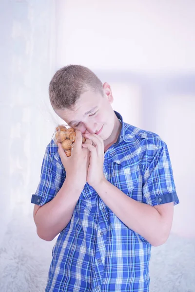 Schattige hongerige tiener jongen met verse kleine Bake snoepjes op witte kamer achtergrond alleen — Stockfoto