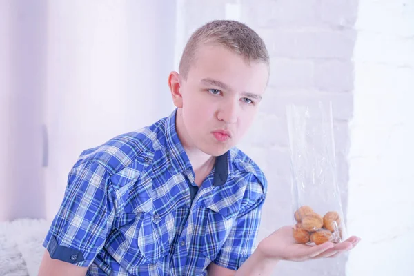 Χαριτωμένο πεινασμένο έφηβο αγόρι με φρέσκα μικρά γλυκά κέικ σε λευκό φόντο δωμάτιο μόνο — Φωτογραφία Αρχείου