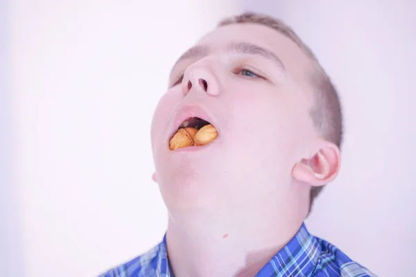 Mignon adolescent affamé garçon avec fraîche petite pâtisserie bonbons sur fond de chambre blanche seul — Photo