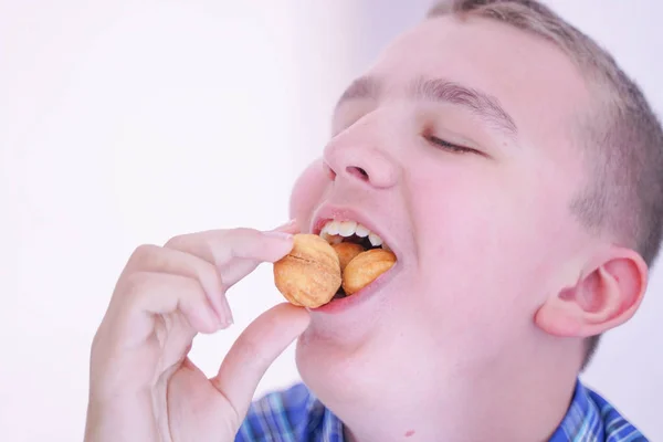 Schattige hongerige tiener jongen met verse kleine Bake snoepjes op witte kamer achtergrond alleen — Stockfoto