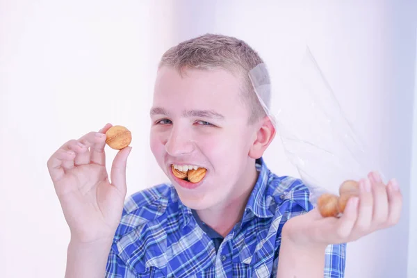Aranyos éhes tinédzser fiú, friss kis sütni édességek fehér szoba háttere egyedül — Stock Fotó