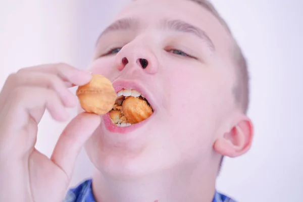 Bonito fome adolescente menino com fresco pequeno assar doces no branco quarto fundo sozinho — Fotografia de Stock