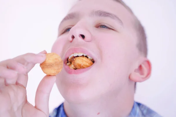 Aranyos éhes tinédzser fiú, friss kis sütni édességek fehér szoba háttere egyedül — Stock Fotó