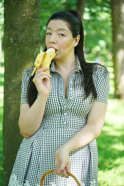 Bastante más tamaño asiático chica comiendo plátano en la ciudad verano parque solo — Foto de Stock