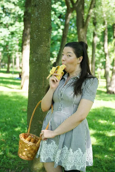 Bonito plus size asiático menina comer banana no o cidade verão parque sozinho — Fotografia de Stock