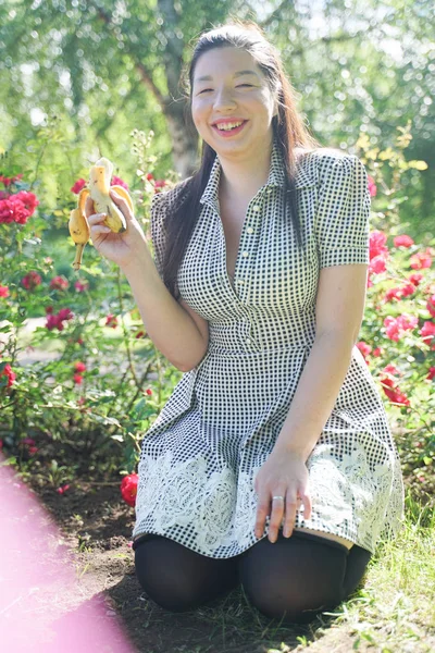 Bonito plus size asiático menina comer banana no o cidade verão parque sozinho — Fotografia de Stock