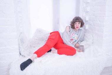 Beyaz pencere üzerinde oturan güzel yetişkin kadın.