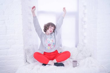 Beyaz pencere üzerinde oturan güzel yetişkin kadın.