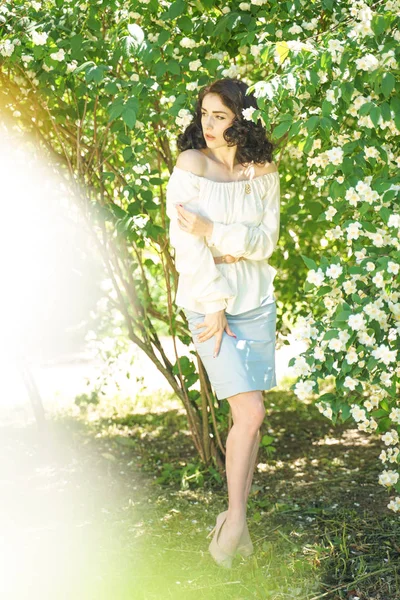 Dziewczyna stoi wśród krzewów jaśminu i wdycha zapach kwiatów — Zdjęcie stockowe