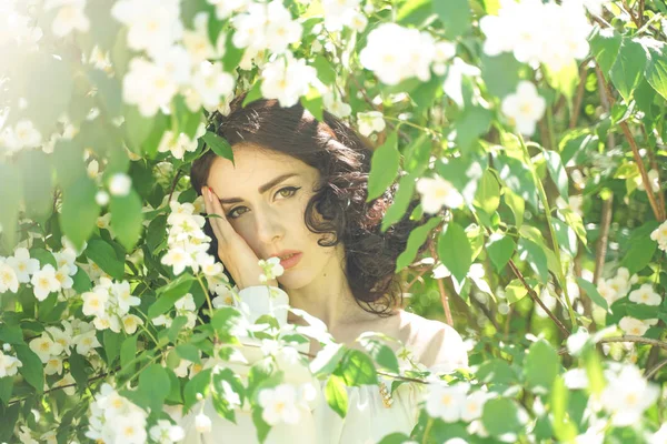 Dziewczyna stoi wśród krzewów jaśminu i wdycha zapach kwiatów — Zdjęcie stockowe
