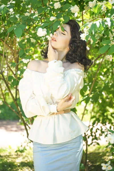 A menina está entre os arbustos Jasmine e inala a fragrância das flores — Fotografia de Stock