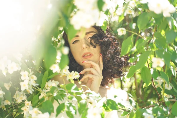 A menina está entre os arbustos Jasmine e inala a fragrância das flores — Fotografia de Stock