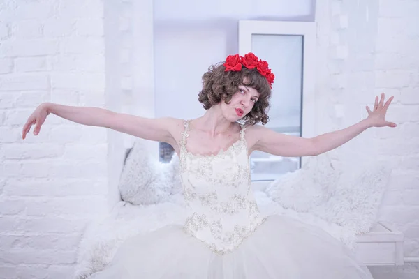 Modelo de moda adulta usando rosas vermelhas na cabeça e vestido de noiva de casamento branco no fundo branco . — Fotografia de Stock