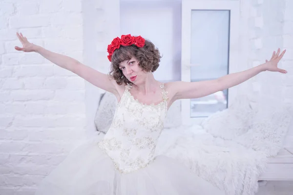 Felnőtt divat modell viselése piros rózsa a fej és a fehér esküvői menyasszony ruha fehér háttér. — Stock Fotó