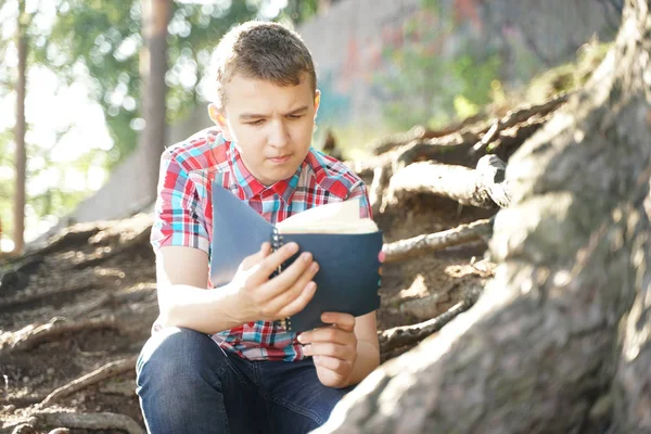 Adolescente leyendo libro de ejercicios sobre la naturaleza — Foto de Stock