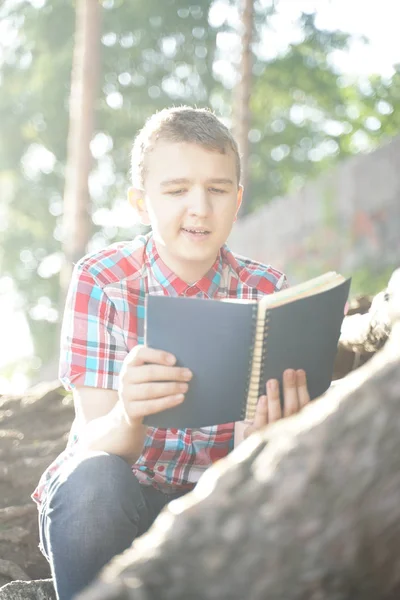 Adolescente leyendo libro de ejercicios sobre la naturaleza — Foto de Stock