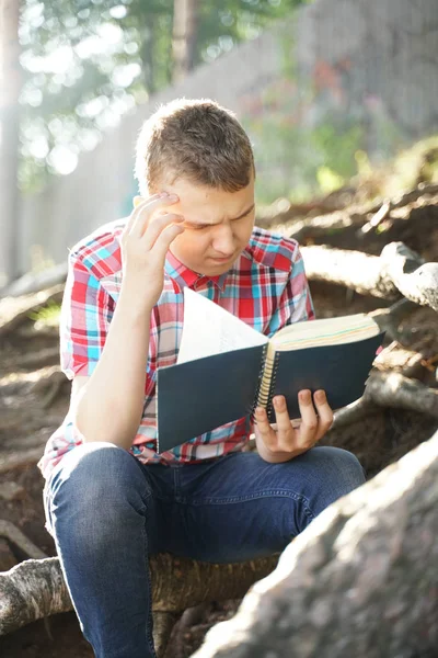 Adolescente leyendo libro de ejercicios sobre la naturaleza —  Fotos de Stock