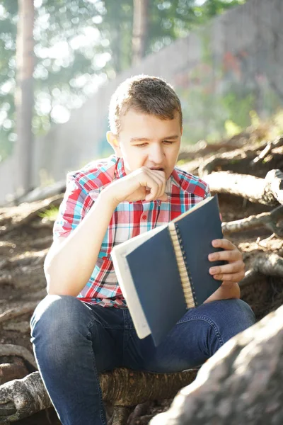 Adolescente ragazzo lettura libro di esercizi sulla natura — Foto Stock