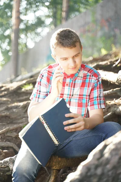 Adolescente leyendo libro de ejercicios sobre la naturaleza — Foto de Stock