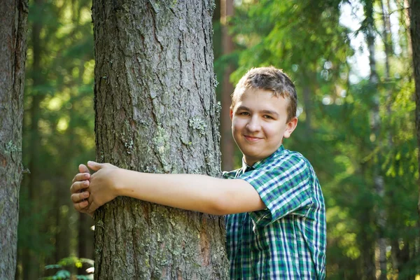 Έφηβος αγόρι αγκαλιά και αγάπη μεγάλο δέντρο στο δάσος μόνο την ημέρα του καλοκαιριού — Φωτογραφία Αρχείου