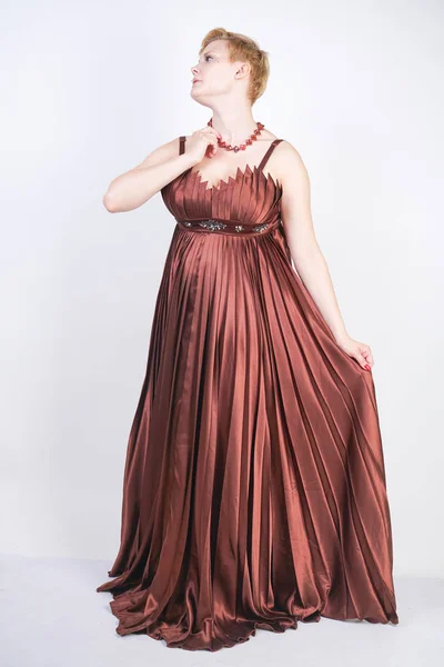 Young pregnant girl in a long brown pleated evening dress — Stock Photo, Image