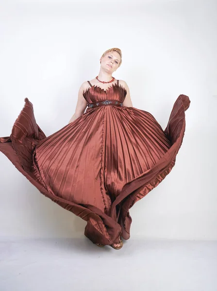 Young pregnant girl in a long brown pleated evening dress — Stock Photo, Image