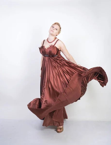 young pregnant girl in a long brown pleated evening dress