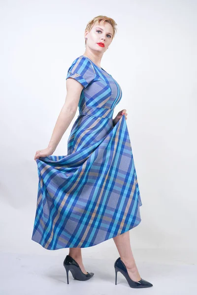 Cute plus size blonde girl in a long rustic plaid blue dress — Stock Photo, Image